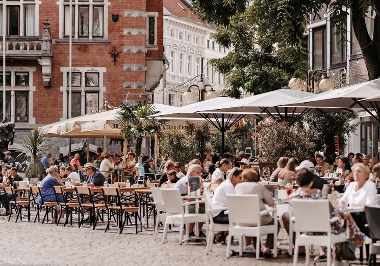 Menschen in den Cafés am Rathausplatz. Foto: Mittwollen und Gradetchliev