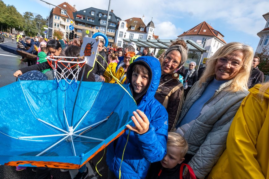 Zuschauer mit Regenschirm am Straßenrand beim Festumzug. Foto: Sascha Stüber