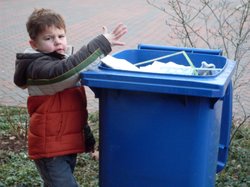 Ein Kind wirft Papier in die blaue Tonne. Foto: Stadt Oldenburg