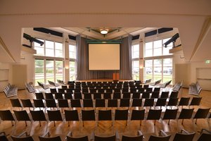 Veranstaltungssaal des PFL mit heruntergelassener Leinwand, Blick von der Eingangstür. Foto: Jörg Hemmen.