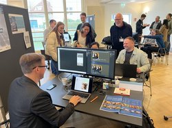 Interessierte Personen am Infostand zu Bildgenerierung. Grafik: Stadt Oldenburg Interessierte Personen am Infostand zu Bildgenerierung. Grafik: Stadt Oldenburg