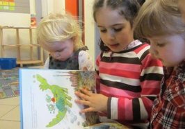 Drei Kinder schauen sich ein Buch an. Foto: Stadt Oldenburg