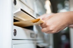 Hand, die Post in einen Briefkasten steckt. Foto: apops/Fotolia.com