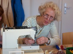 Die Kursleitung des Nähkurses sitzt an der Nähmaschine und lächelt in die Kamera. Foto: Stadt Oldenburg