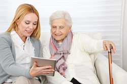 Eine Frau zeigt einer älteren Dame etwas auf einem Tablet. Foto: Robert Kneschke/Fotolia