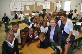 Besuch in der Floradale Primary School in Nompumelelo: OB Krogmann sitzt mit der Schulleiterin umringt von Schülerinnen und Schülern in einem Klassenzimmer. Foto: Stadt Oldenburg