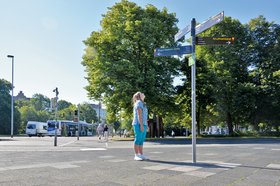 Kind vor einem Oldenburger Wegweiser. Foto aus dem Projekt „Zuhause in der Fremde – inszenierte Fotografie“ (www.sociallandartproject.de). slap e.V.