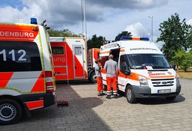 Fahrzeuge und Mitarbeitende der Johanniter-Unfall-Hilfe auf einem Hof. Foto: Johanniter Oldenburg