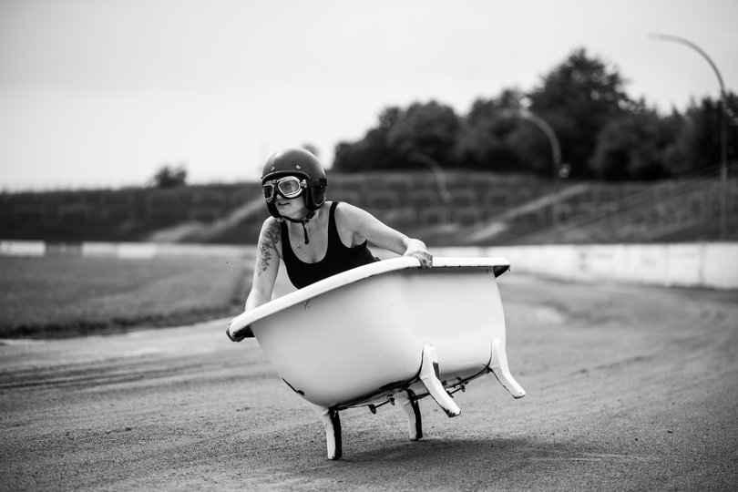 Frau mit Motorradhelm in einer Badewanne. Foto: Carola Bührmann