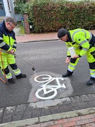 Zwei Männer tragen ein Piktogramm eines Fahrrads auf. Foto: Stadt Oldenburg