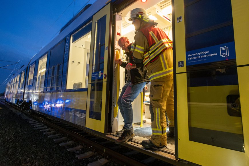 Ein Feuerwehrmann hilft einem Mann aus dem Zug. Foto: Sascha Stüber