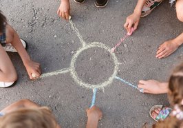 Kinder zeichnen eine Sonne mit Kreide auf die Straße. Foto: Freepik