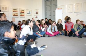 Kinder aus Oldenburg und Groningen sitzen bei einer Lesung auf dem Boden und hören gespannt zu. Foto: Stadt Oldenburg