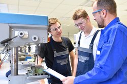 Zwei Auszubildende erhalten in einer Metallbauer-Werkstatt eine Geräteeinweisung von ihrem Ausbilder. Foto: stafftastic