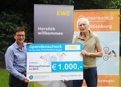 Marion Rövekamp, Vorständin EWE AG, übergibt den Scheck für das Erreichen des achten Etappenziels an Hansjürgen Otto, Vorsitzender BildungsChancen im Blick. Foto: Stadt Oldenburg