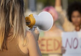 Frau mit Megaphone auf einer Demo. Foto: Freepik