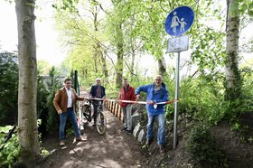 Vier Männer, einer davon auf dem Fahrrad, stehen an einem Absperrband und schneiden es durch. Foto: Sascha Stüber