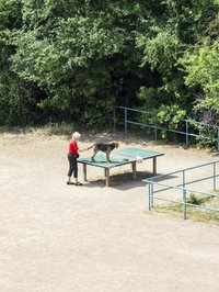 Eine ältere Frau mit einem Hund, der auf einer Tischtennisplatte steht. Foto: Hayahisa Tomiyasu