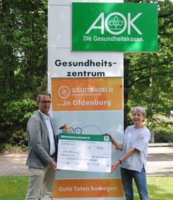 André Kerber, Regionaldirektor der AOK, übergibt den Scheck für das Erreichen des zweiten Etappenziels an Heike Schwarz von kids aktiv. Foto: Stadt Oldenburg