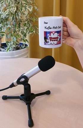 Eine Hand hält eine Tasse mit dem Aufdruck „Inas Kaffee-Pott-Cast. Foto: Stadt Oldenburg