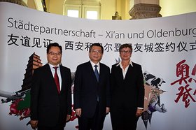 Generalkonsul Sun Congbin, Wang Yongkang, Parteisekretär der Stadt Xi’an, und Erste Stadträtin Silke Meyn stehen vor einer Wand mit der Aufschrift „Städtepartnerschaft Xi'an und Oldenburg“. Foto: Stadt Oldenburg