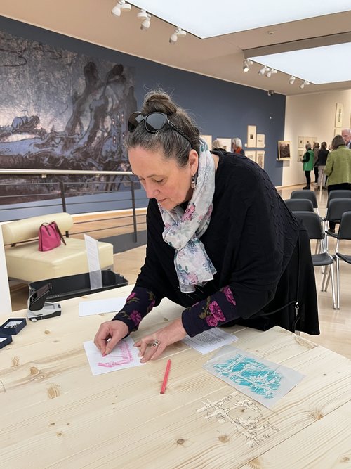 Kunstvermittlerin Geraldine Dudek zeigt die Frottage von Janssen-Motiven am Vermittlungstisch in der Ausstellung „Janssen und das Holz“. Foto: Horst-Janssen-Museum Foto: Horst-Janssen-Museum