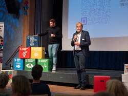 Zuschauerinnen und Zuschauer hören Redner auf der Bühne zu. Foto: Grafikstudio17 Zuschauerinnen und Zuschauer hören Redner auf der Bühne zu. Foto: Grafikstudio17