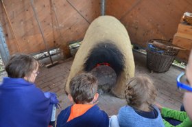 Kinder nehmen teil am Projekt „Backen im Steinzeitofen“. Foto: Landesmuseum Natur und Mensch