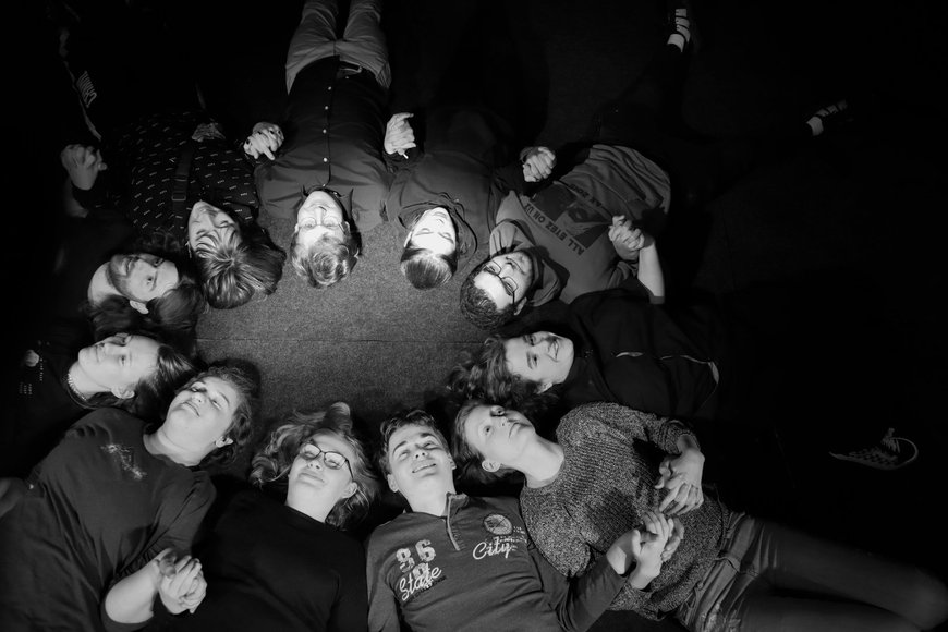 Jugendliche im Kreis auf dem Rücken liegend und lächelnd schwarz/weiß. Foto: Stadt Oldenburg
