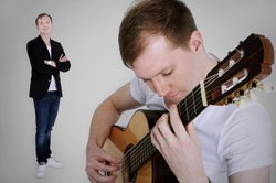 Mann mit blauem Jacket und weißem T-Shirt spielt Gitarre