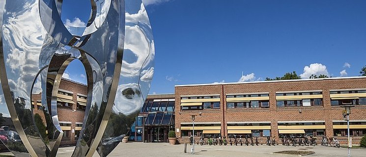 Skulptur aus spiegelndem Metall, im Hintergrund das Backsteingebäude des Rathauses von Høje-Taastrup. Foto: Claus Björn Larsen