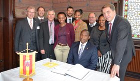 Gruppenbild um den Minister, der sich ins Gästebuch einträgt. Auf dem Tisch steht ein Wimpel mit dem Oldenburger Wappen. Foto: Stadt Oldenburg