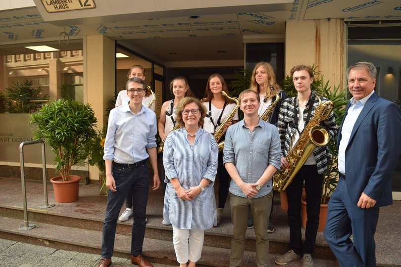 Freuen sich, dass die Musikschule den Betrieb aufnehmen kann: Holger Denckmann, Christiane Cordes, Philipp Schlüchtermann, Jürgen Krogmann sowie Schülerinnen und Schüler des Ensembles „Brasserie“. Foto: Stadt Oldenburg