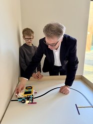 Oberbürgermeister Jürgen Krogmann testet einen kleinen selbstprogrammierten Intech-Roboter, der von Schülern in der Informatik-AG entwickelt wurde. Foto: Stadt Oldenburg