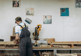 Ein Mann arbeitet an einer Werkbank mit Holz. Foto: Yura Forrat/pexels