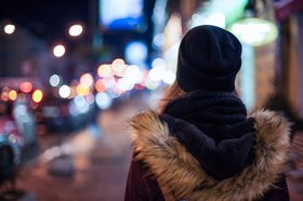 Frau auf einer nächtlich beleuchteten Straße. Foto: finwal89/AdobeStock