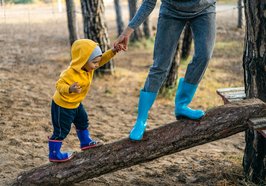 Mutter und Kind balancieren über einen Baumstamm. Foto: Alexandr Podvalny/Pexels 