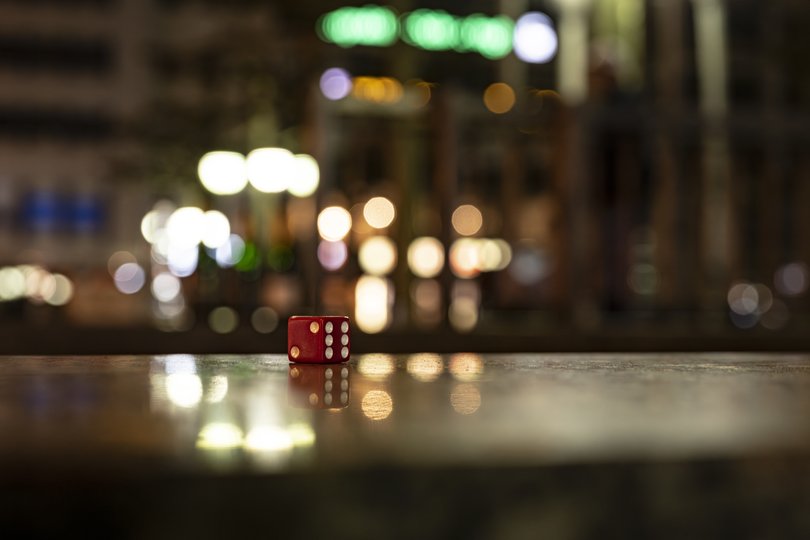 Ein roter Würfel vor verschwommenen Lichtern. Foto: Manfred Mauermann Ein roter Würfel vor verschwommenen Lichtern. Foto: Manfred Mauermann