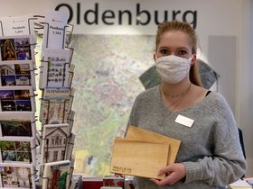 Auszubildende in der Oldenburg-Info im Lappan mit zwei Fliegerhorst-Schneidebrettern. Foto: Oldenburg Tourismus und Marketing GmbH