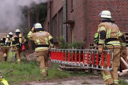 Zwei Kameraden der Feuerwehr tragen eine Leiter zu einem brennendes Haus. Foto: Feuerwehr Oldenburg