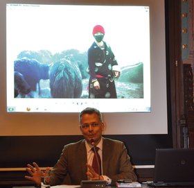 Christian Geinitz auf der Lesung zu „Chinas verborgene Schätze“, im Hintergrund eine Leinwand, auf die ein Foto projiziert wird. Foto: Stadt Oldenburg