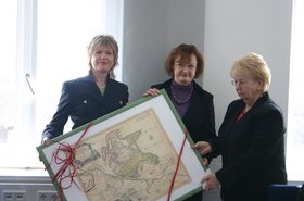 Landrätin von Rügen Kerstin Kassner und Kreistagspräsidentin Gisela Lemke und Rita Schilling halten ein großes gerahmtes Bild mit einer Schleife. Foto: Stadt Oldenburg