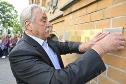 Dietmar Schütz von der Oldenburger Bürgerstiftung beim Anbringen der vier Erinnerungszeichen an der Hauswand in der Roggemannstraße 25. Foto: Sascha Stüber