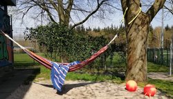 Eine rote Hängematte zwischen zwei Bäumen im Garten der Freizeitstätte Kreyenbrück. Foto: Stadt Oldenburg