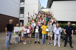 Viele Kinder stehen auf einer Treppe und jubeln. Im Vordergrund werden die verschiedenen Urkunden in die Kamera gehalten. Foto: Sascha Stüber