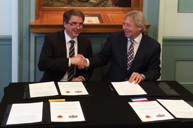 Groningens Bürgermeister Peter den Oudsten und Oberbürgermeister Jürgen Krogmann sitzen nebeneinander und geben sich die Hand. Vor Ihnen liegen mehrere Ausgaben des Letter of Intent. Foto: Stadt Oldenburg