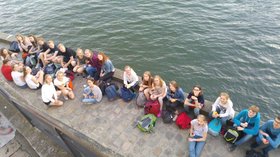 Jugendlichen sitzen nebeneinander am befestigten Ufer der Seine. Foto: Imke Glockauer-Götting