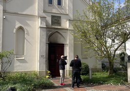 Blick auf die Synagoge nach dem Brandanschlag. Zwei Menschen mit Kamera stehen vor der Tür. Foto: Stadt Oldenburg