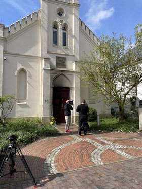 Blick auf die Synagoge nach dem Brandanschlag. Zwei Menschen mit Kamera stehen vor der Tür. Foto: Stadt Oldenburg