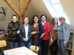 Iranische Frauen stehen vor einer Bücherwand mit persischen Büchern und lächeln in die Kamera. Foto: Stadt Oldenburg